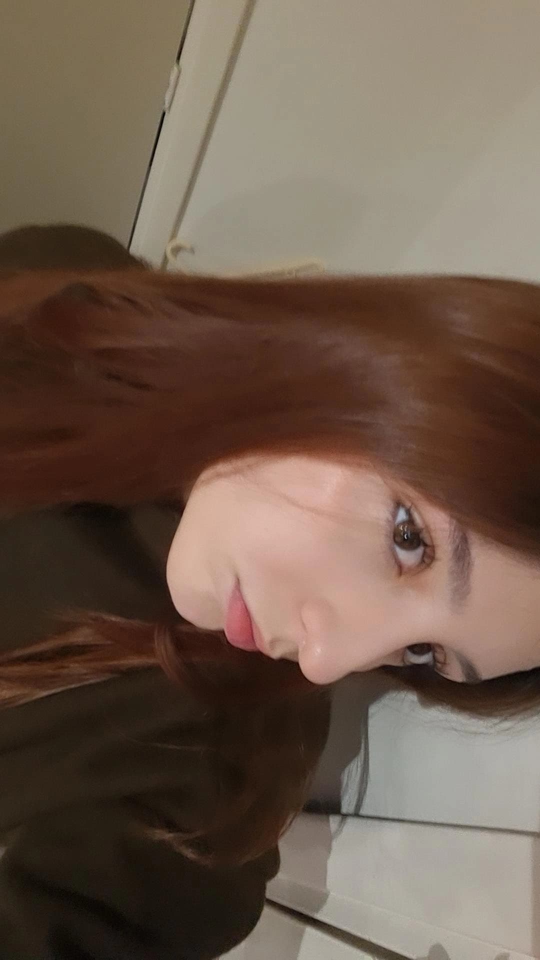 Close-up side profile of a person with long, straight auburn hair and fair skin.
